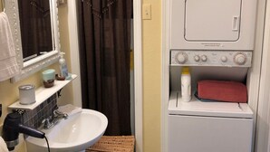 Une petite salle de bain comprenant un lavabo, un miroir et un lave-linge.