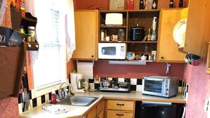 Une cuisine compacte avec des meubles en bois, un four à micro-ondes, un grille-pain et un petit réfrigérateur.