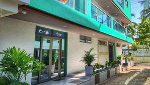 A modern building with a green facade, multiple balconies, and a ground-level entrance with glass doors. - Dreimar hotel boutique - La Boquilla Cartagena. (Cartagena)