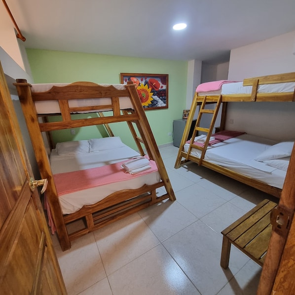 A room with two bunk beds, a small wooden table, and a colorful painting on the wall. - Dreimar hotel boutique - La Boquilla Cartagena. (Cartagena)
