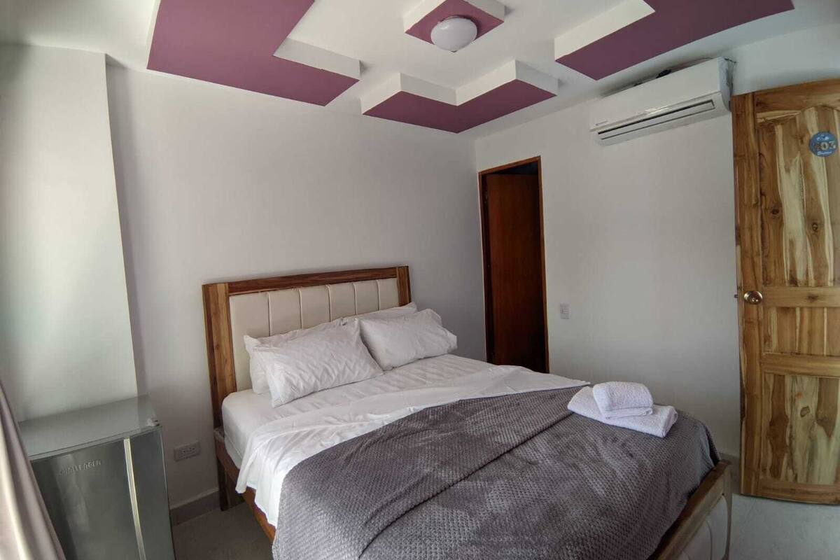 Une chambre à coucher avec un lit, une armoire en bois et un plafond orné de motifs géométriques.