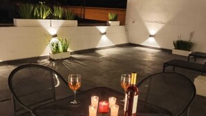 An outdoor dining area with a table and chairs, candles, and a bottle of wine. - Hotel Miranda (Querétaro)