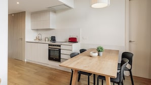 Een moderne keuken met witte kasten, een houten eettafel en zwarte stoelen.