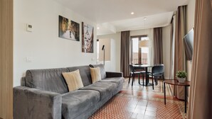 Ein modernes Wohnzimmer mit grauem Sofa, einem Esstisch mit Stühlen und einem Fernseher auf einem Lowboard.