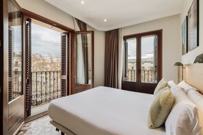 A hotel room with a large bed, a balcony with a view of the city, and a door leading to an outdoor area. - OLA LIVING BOQUERIA 4 (Barcelona)