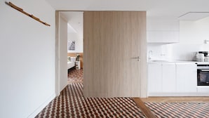 A modern kitchen with white cabinets, a wooden door, and a patterned floor. - OLA LIVING BOQUERIA 5 (Barcelona)