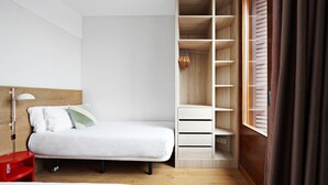 A bedroom with a bed, a wardrobe, and a window with curtains. - OLA LIVING BOQUERIA 5 (Barcelona)