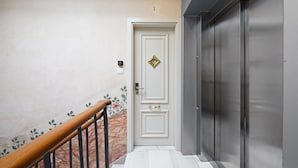 A hallway with a white door, a wooden handrail, and a marble-patterned wall. - OLA LIVING BOQUERIA 5 (Barcelona)