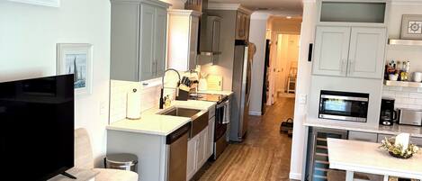 A modern kitchen with white cabinetry, a central island, and a dining area with a white table and chairs.