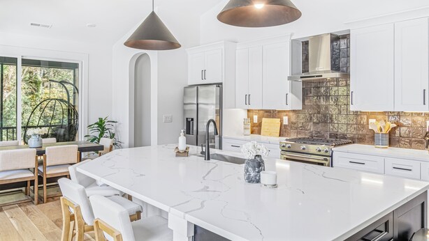 A modern kitchen with a large island, white cabinetry, stainless steel appliances, and pendant lighting. - Modern Home Near Uptown & Camp North End - Sleeps 12, Sports-Themed Game Room (Charlotte)