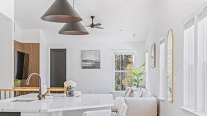 A modern kitchen with a large island, white cabinetry, and a pendant light. - Modern Home Near Uptown & Camp North End - Sleeps 12, Sports-Themed Game Room (Charlotte)
