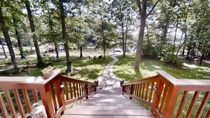 Una escalera de madera que lleva a un parque con mesas para picnic y vistas a un lago.