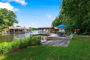 A riverside dock with wooden platforms, covered seating areas, and a grassy area with outdoor furniture. - Lakefront - Spacious 5-bedroom house on Lake Anna - Public Side (Bumpass)