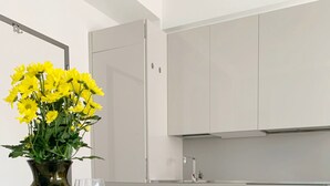 A modern kitchen with white cabinets, a dining table set with blue and white plates, and a vase with yellow flowers. - Cardano Blue Suite - 5 min da Stazione Centrale (Milan)