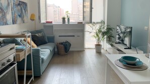 A modern apartment with a sofa, a dining table, a TV, and a window with a city view. - Cardano Blue Suite - 5 min da Stazione Centrale (Milan)