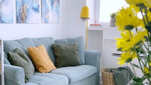 A light blue sofa with multiple cushions, a yellow floor lamp, and a wicker basket with a green blanket. - Cardano Blue Suite - 5 min da Stazione Centrale (Milan)