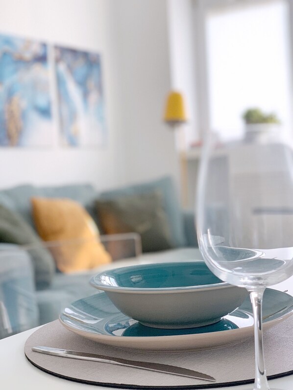 A dining table with a clear glass wine glass, a plate, and a bowl.