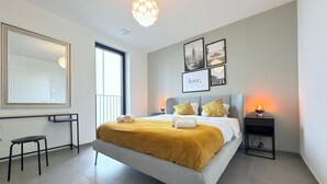 Una camera da letto moderna con un letto grande, un comodino con una lampada, uno specchio e opere d'arte alle pareti.