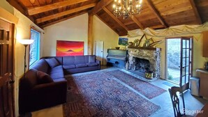 A cozy living room with a large sofa, a fireplace, and a chandelier.