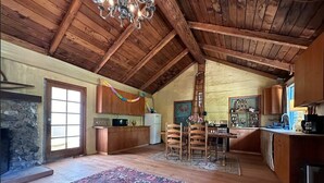A spacious loft-style kitchen with wooden beams, a stone fireplace, and a large rug.