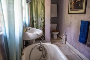 Un baño con bañera, dos lavamanos, inodoro y cortina de ducha.