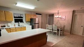A modern kitchen with wooden cabinets, a central island, and a dining area with a chandelier.