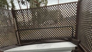 A hot tub with a wooden deck and a lattice fence in the background.