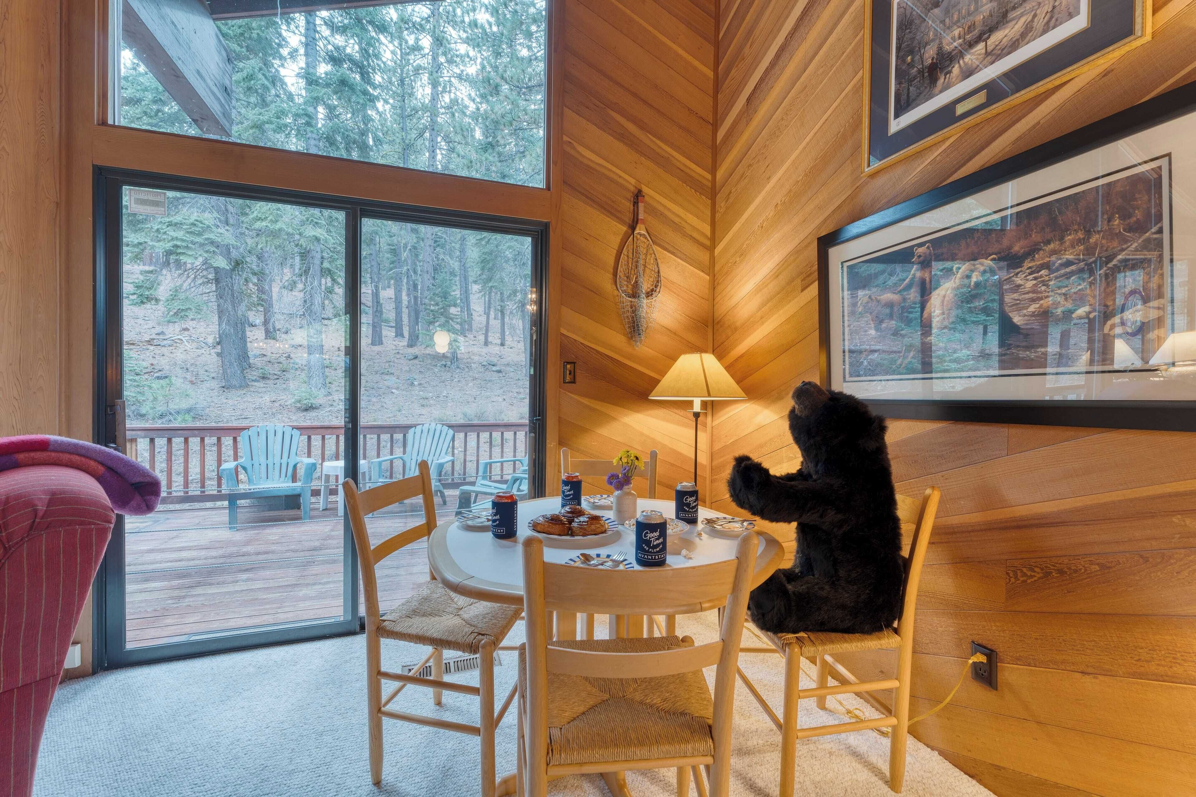 Interior acogedor de una cabaña con una mesa de comedor lista para dos personas, una lámpara y cuadros en las paredes.
