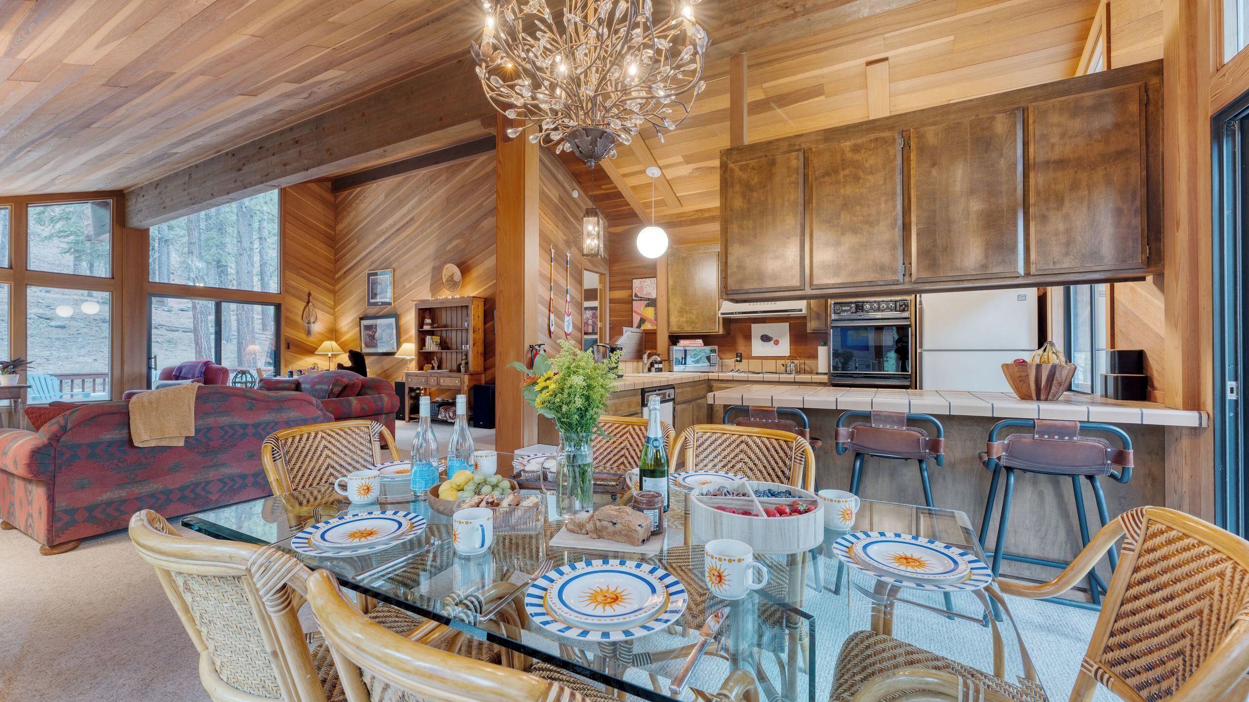 A spacious living area with a glass dining table, wicker chairs, and a large sofa.