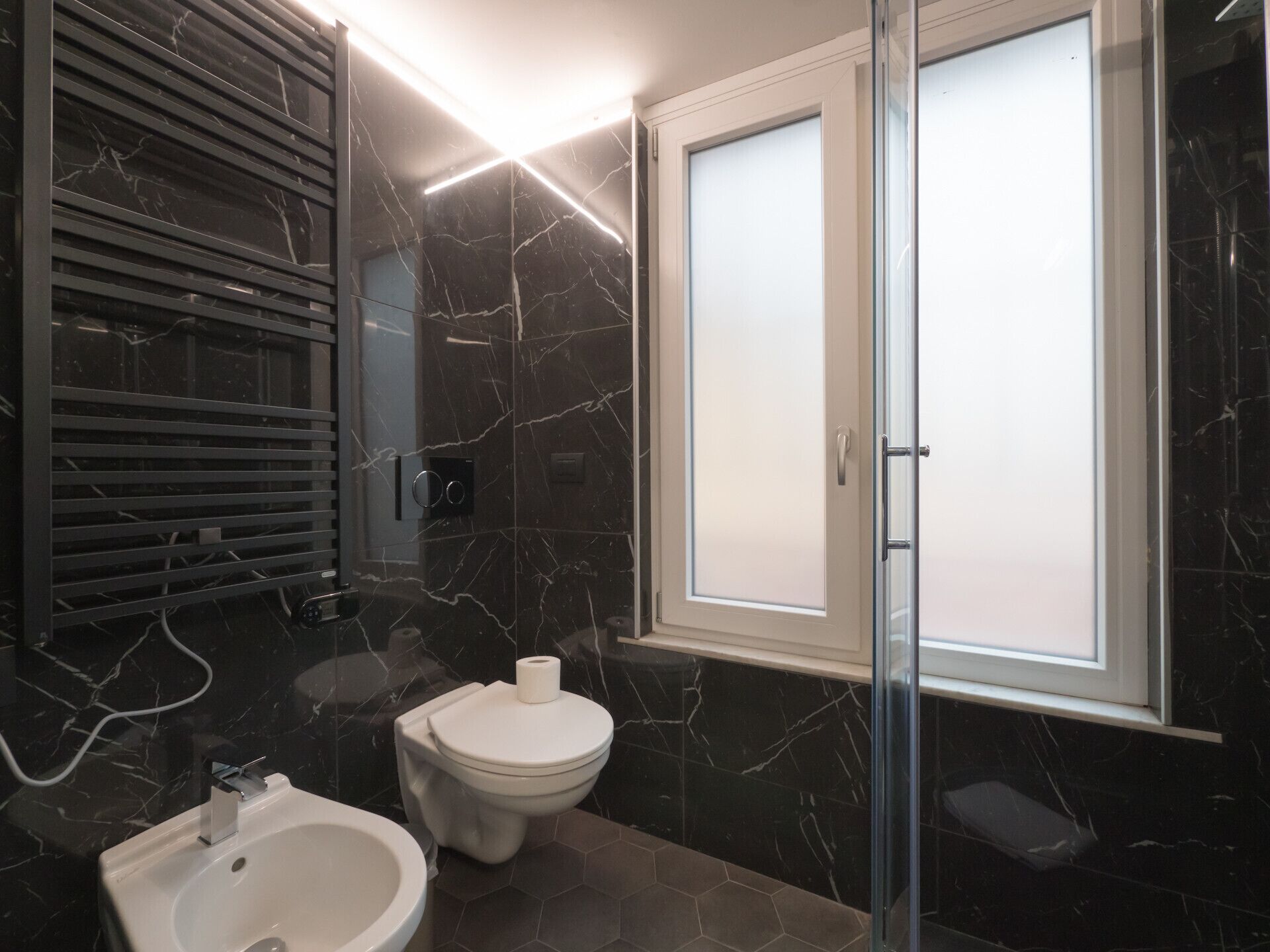 Ein modernes Badezimmer mit Toilette, Bidet und einer Duschkabine aus Glas.