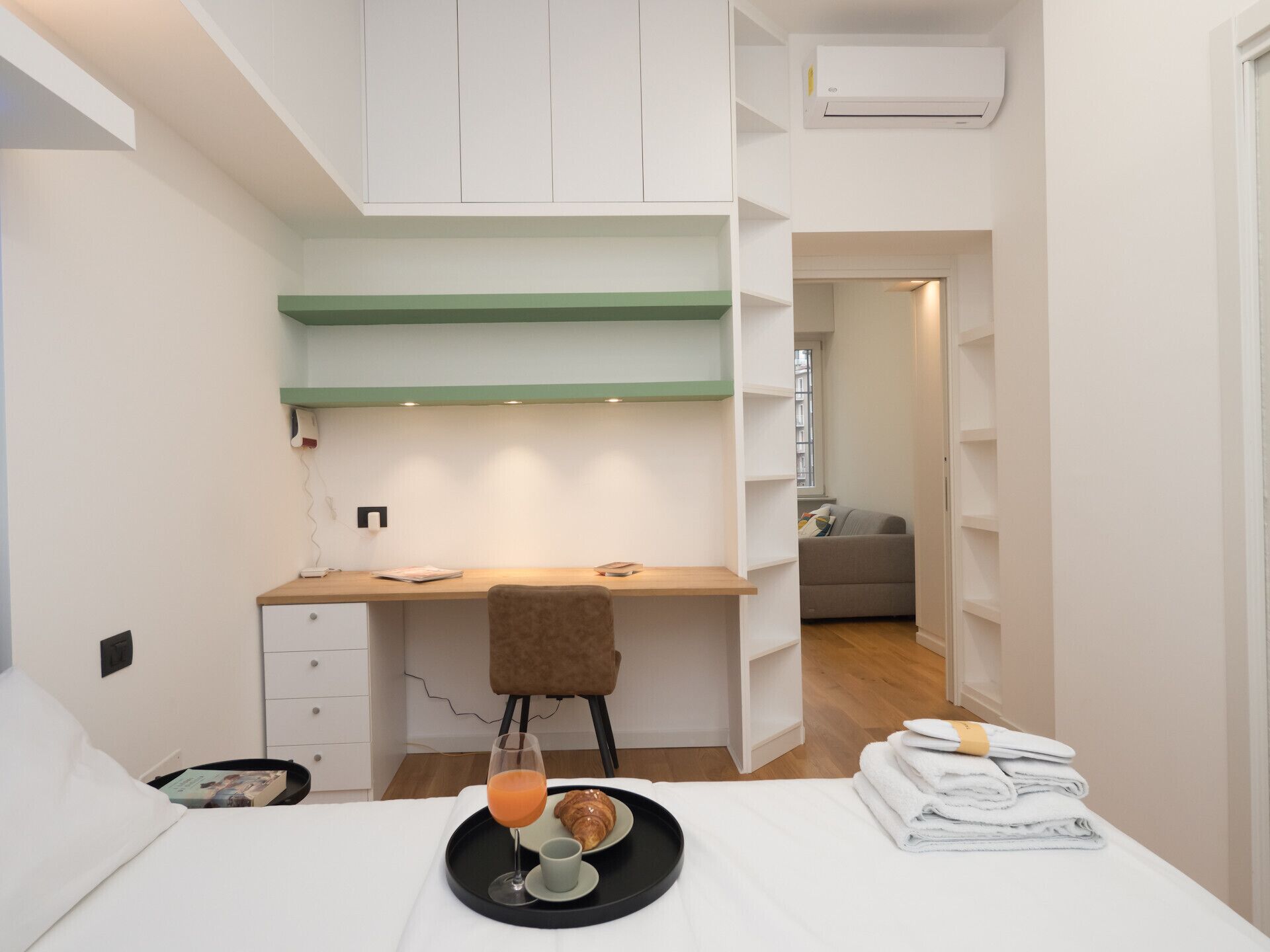 Een knus slaapkamer met een bureau, een stoel, een bed en een klein kitchenette.