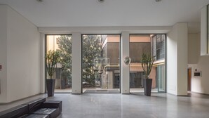 A spacious lobby with a modern design, featuring a seating area, large windows, and potted plants. - Corso Garibaldi - Modern & Cozy Suite by Rentopolis (Milan)