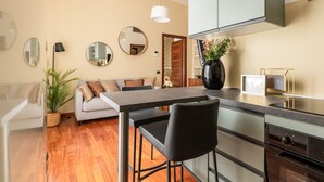 A modern kitchen with a dining area, wooden flooring, and a sofa. - Corso Garibaldi - Modern & Cozy Suite by Rentopolis (Milan)