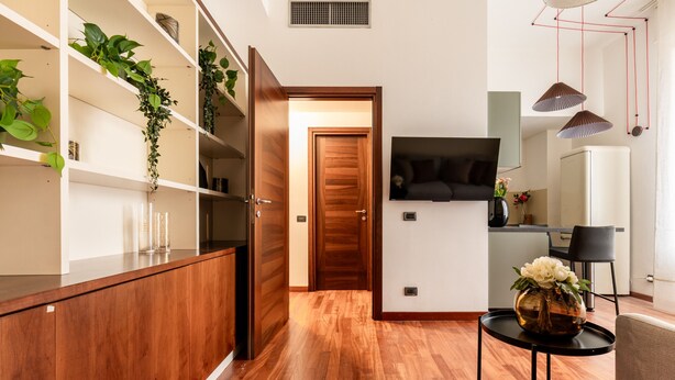 A modern kitchen with wooden cabinets, a black countertop, and a wooden door leading to another room. - Corso Garibaldi - Modern & Cozy Suite by Rentopolis (Milan)