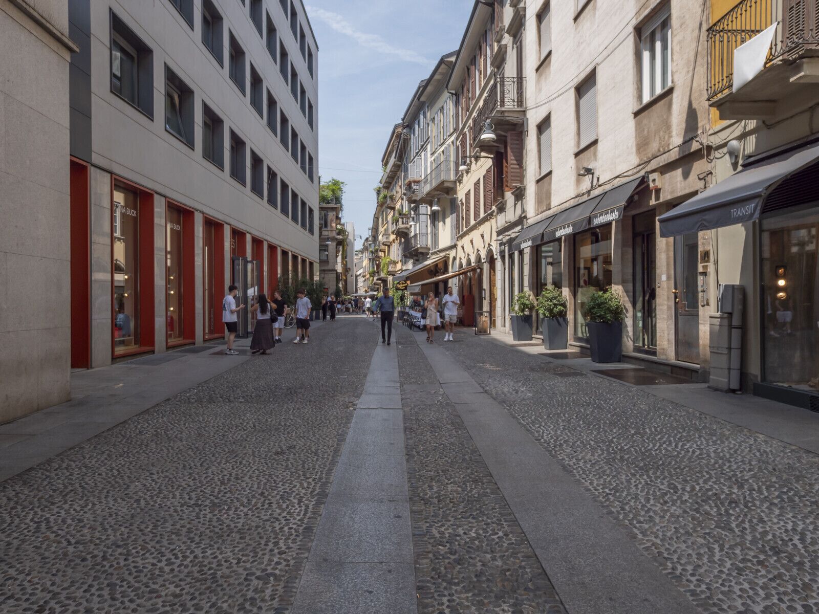 Un carrer empedrat flanquejat per edificis, alguns amb botigues i d'altres amb habitatges.
