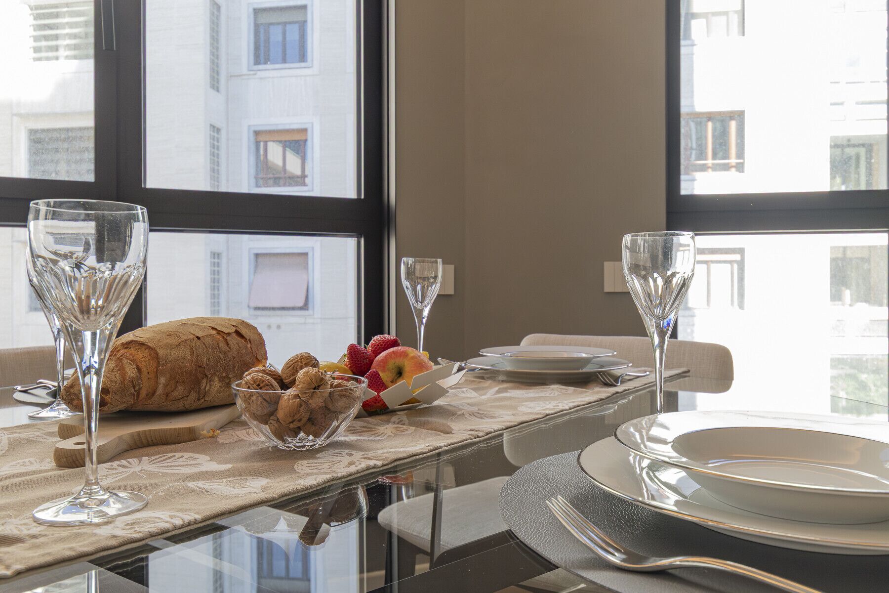 A breakfast table with a croissant, walnuts, strawberries, and a glass of water.