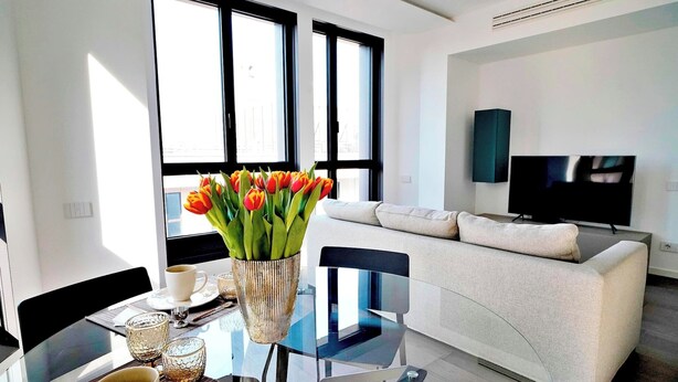 Een moderne woonkamer met een glazen eettafel, een bank en een televisie.