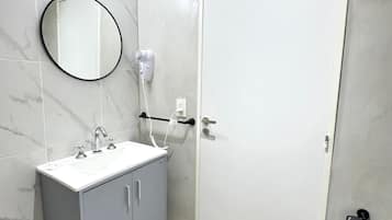 A bathroom with a white sink, mirror, and toilet.