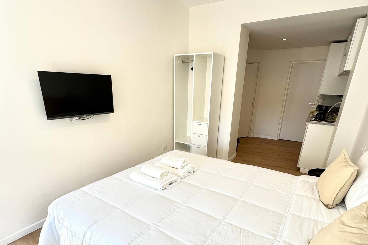 Un dormitorio con cama, televisión, espejo y vestidor.