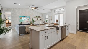 A modern kitchen with white cabinetry, a granite countertop, and a built-in dishwasher.