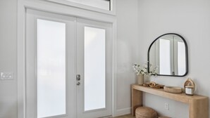 A modern interior with a double door, a wooden console table with decorative items, and a mirror.