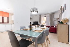 Een moderne woonruimte met een eethoek, keuken en een rode bank.