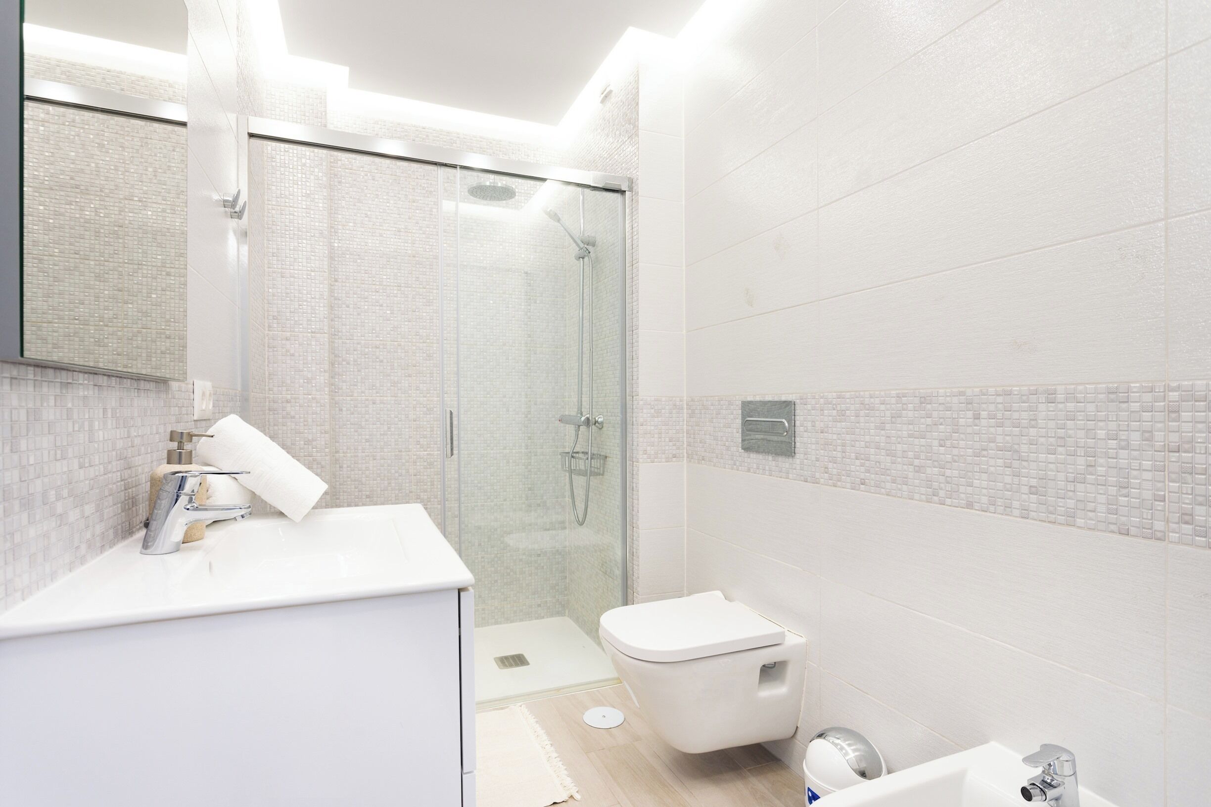 Une salle de bain moderne avec une douche à parois de verre, un lavabo blanc et des toilettes.