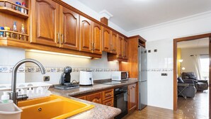 Une cuisine avec des meubles de rangement en bois, un évier jaune, un four à micro-ondes et un réfrigérateur.