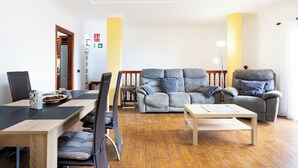 Un salon comprenant un canapé, un fauteuil et une table à manger avec des chaises.