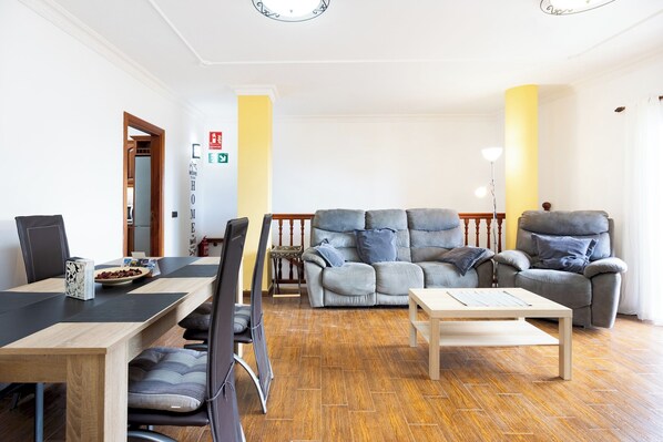 A living room with a sofa, armchair, and a dining table with chairs. - Home2Book Tranquil Spot Buenavista, BBQ & Views (Buenavista del Norte)