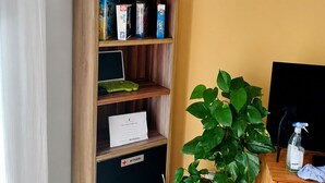 Une pièce avec une bibliothèque en bois, une plante en pot, un bureau avec un ordinateur et un appareil de climatisation.