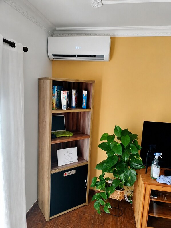 A room with a wooden bookshelf, a potted plant, a desk with a computer, and an air conditioning unit. - Home2Book Tranquil Spot Buenavista, BBQ & Views (Buenavista del Norte)