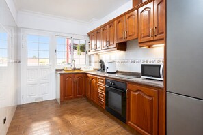A kitchen with wooden cabinets, a stainless steel refrigerator, a microwave, and a dishwasher.