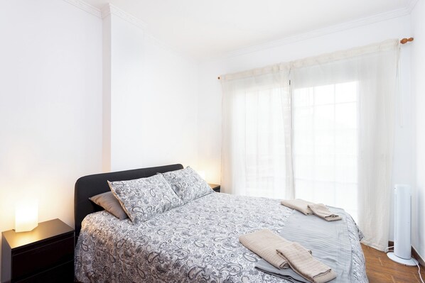 A bedroom with a bed, nightstand, and a radiator.